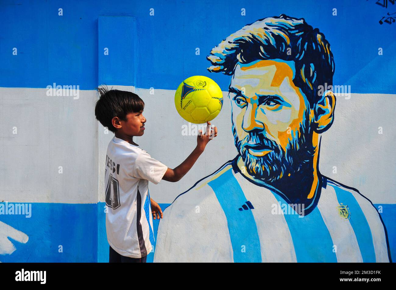 Dec 14, 2022 in Sylhet, Bangladesh: Young Argentina fans Celebrating, poses in front of a mural of his hero, Lionel Messi, win over Croatia in the semi final match last night and qualified for the World Cup Final 2022. Bangladesh,such a country that has never been qualified for any football world cup; but has great love for football and has huge fans followers for both Argentina and Brazil. On December 14, 2022 in Sylhet, Bangladesh (Photo by Md Rafayat Haque Khan/ Eyepix Group) Stock Photo