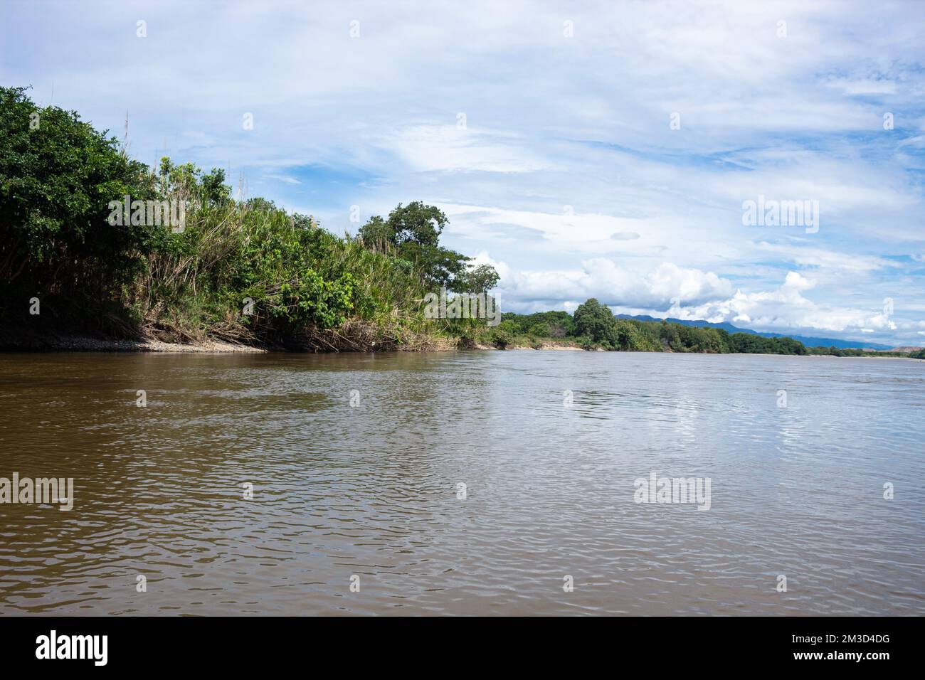 Magdalena River in sunny day with green trees and bushes, clouds and blue sky at background near to Aipe town, Huila Colombia Stock Photo
