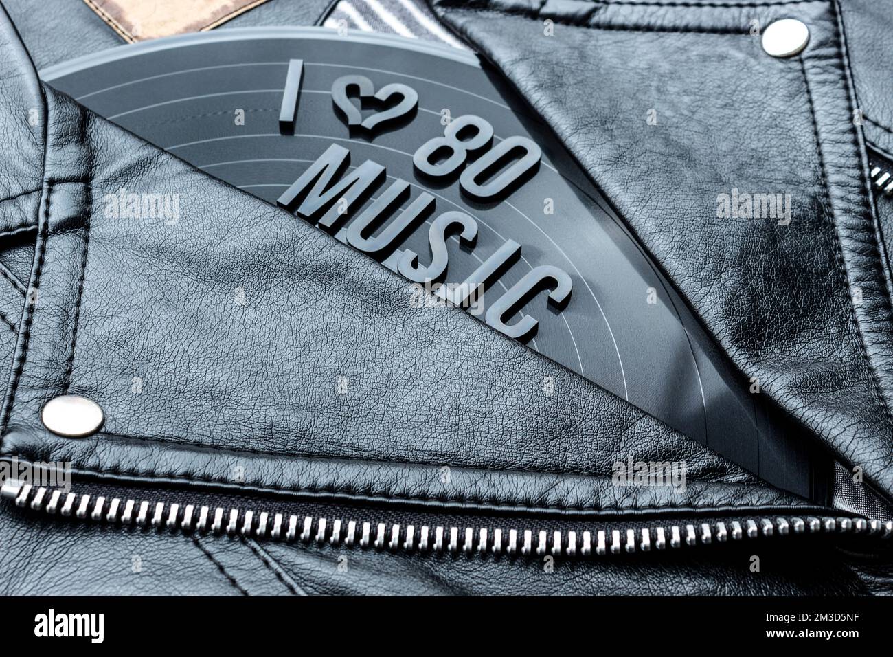 Closeup to a I hearth (love) 80 music lettering art over a black leather biker jacket with LP vinyl disc. Music lover concept, retro photography. Stock Photo