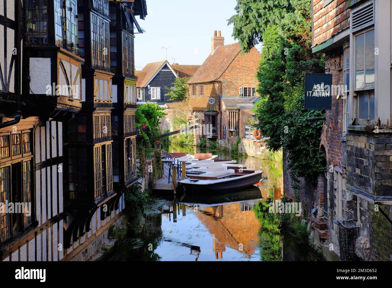 Boats, period buildings and Old Weavers House with mirror reflections in the Great Stour River glowing gold soon before sunset in Canterbury, UK Stock Photo