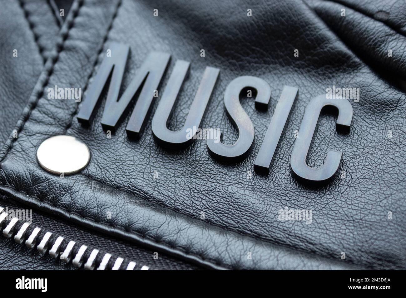 Closeup to a MUSIC black lettering word over a black biker leather jacket. Music lovers and fashion concept style Stock Photo