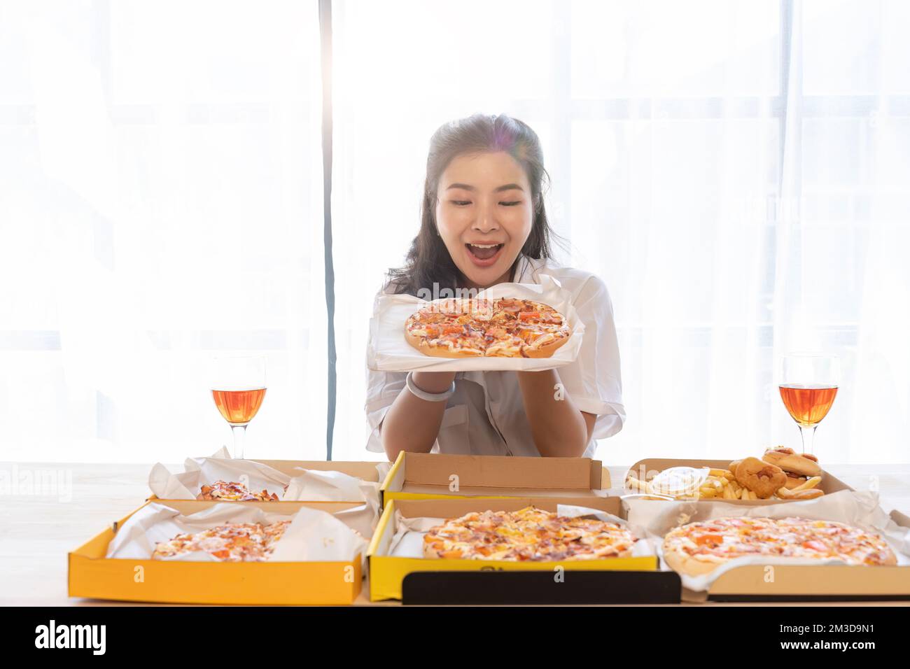 Portrait of Asian celebrate Christmas with champagne and eating pizza at home. Joy of holiday party with friends or colleague concept Stock Photo