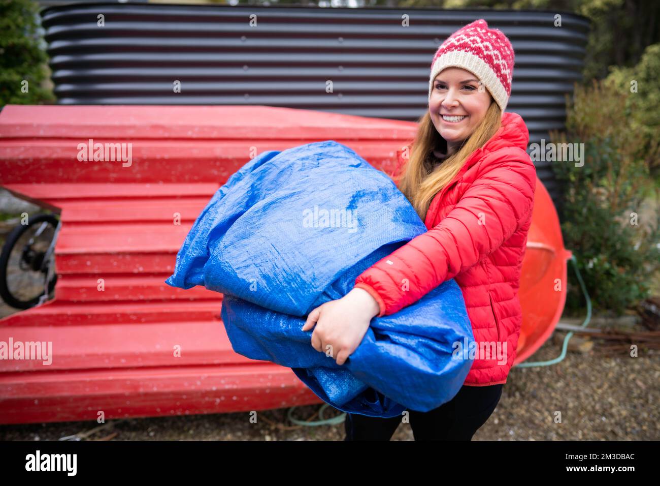 woman folding up a tarp at a campground in australia. camping tant and
