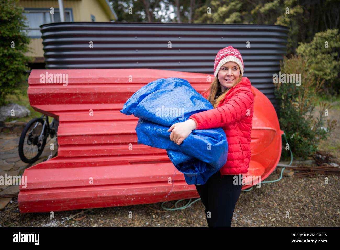 woman folding up a tarp at a campground in australia. camping tant and