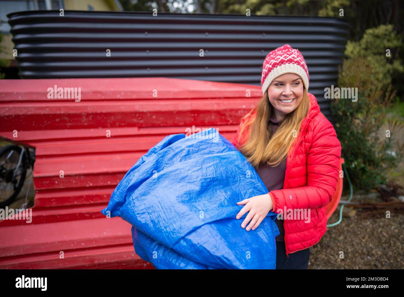woman folding up a tarp at a campground in australia. camping tant and