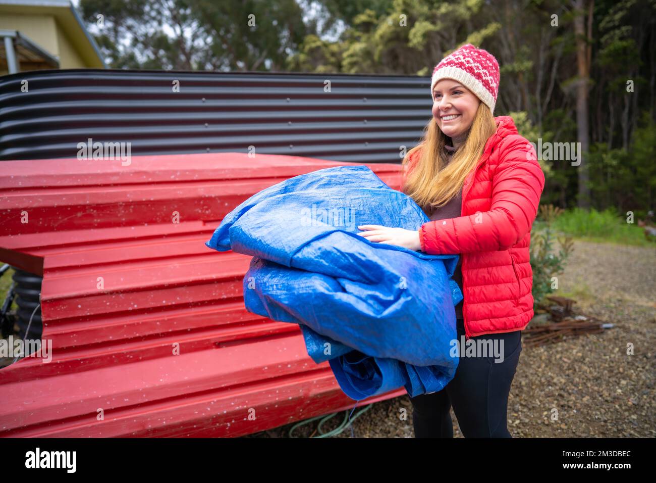 woman folding up a tarp at a campground in australia. camping tant and