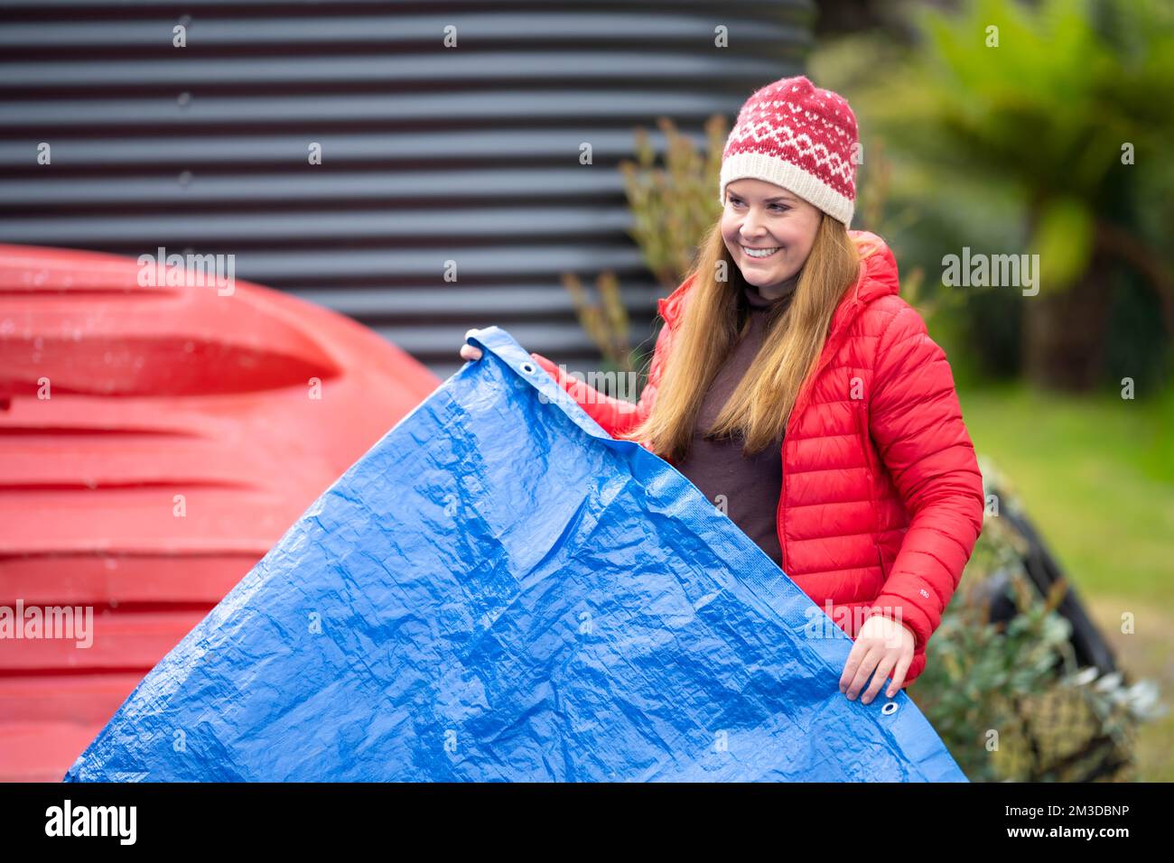 woman folding up a tarp at a campground in australia. camping tant and