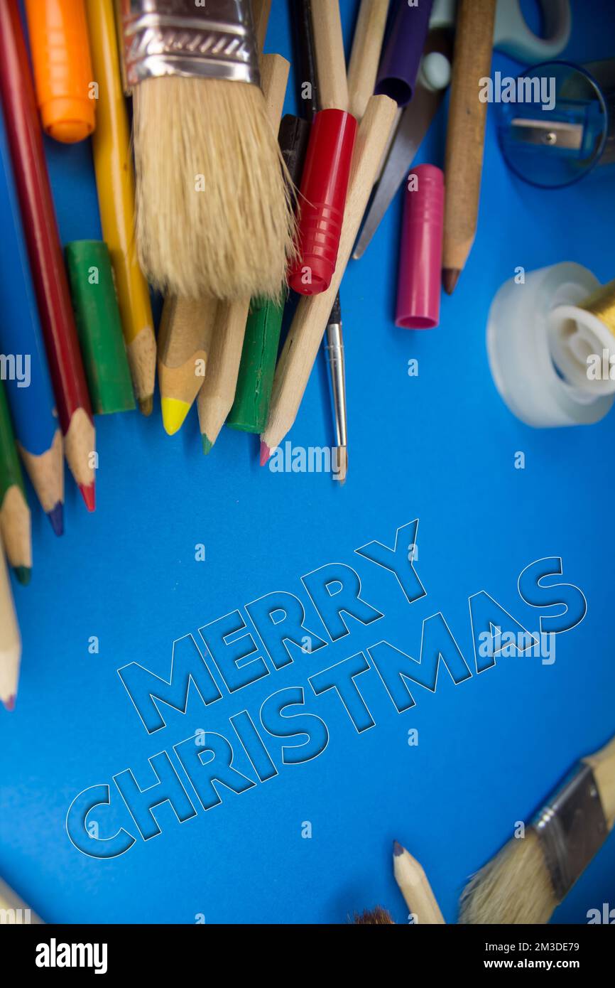 Overhead shot of school supplies with Merry Christmas text. Brushes, pencils, artistic tools. Art And Craft Work Tools. Stock Photo
