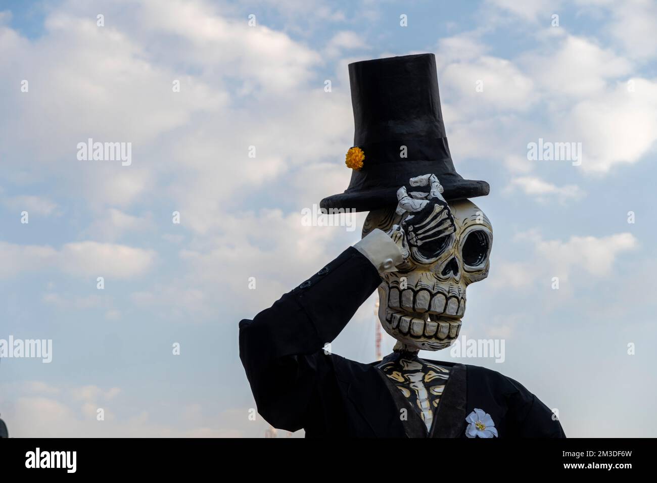 giant paper skulls dressed in black costume in the background blue sky with clouds Stock Photo