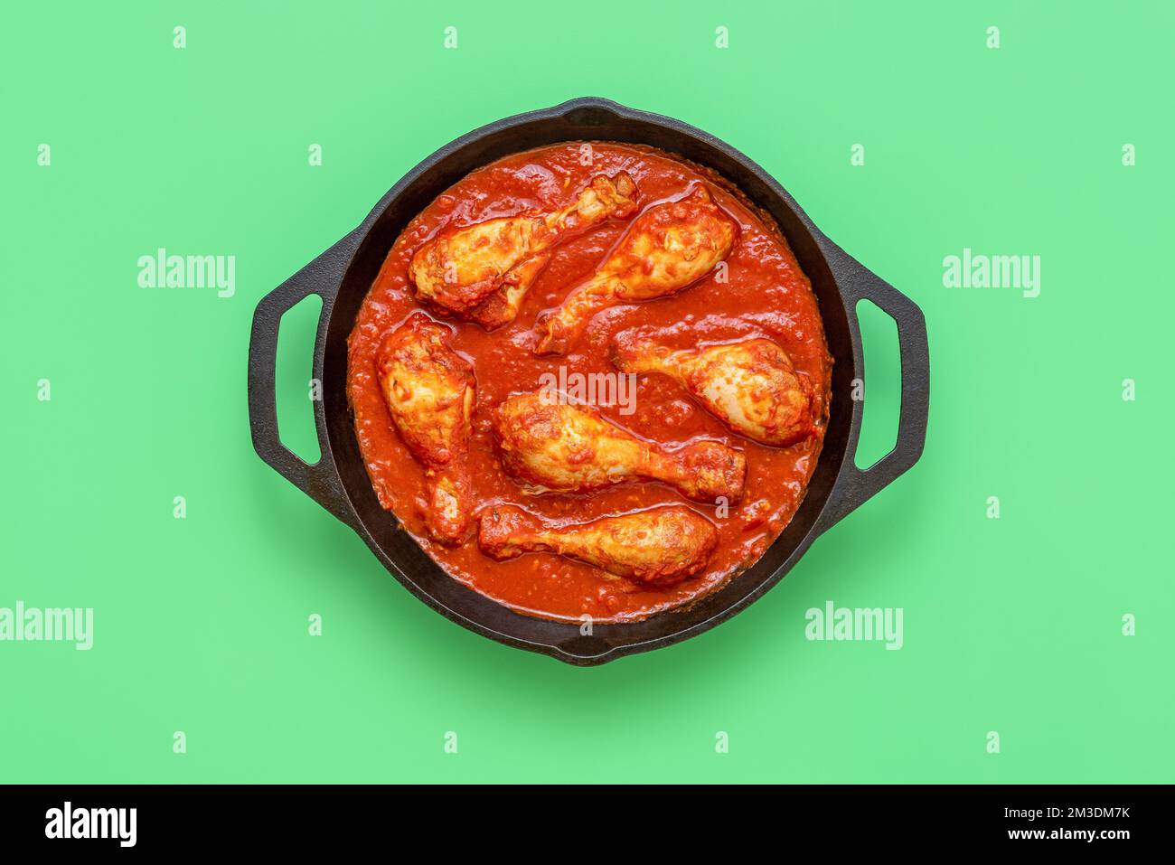 Top view with chicken stew in an iron cast pot minimalist on a green