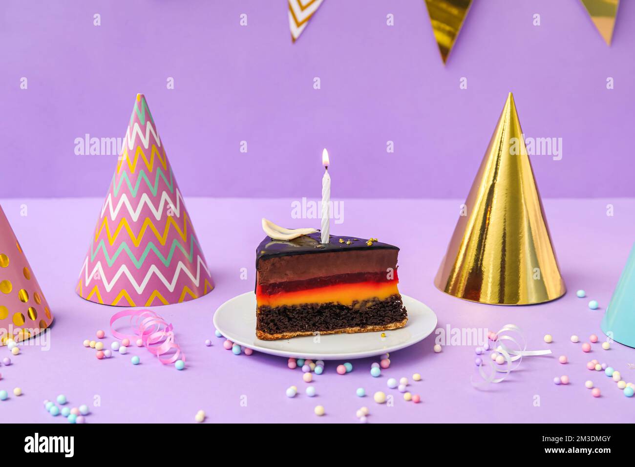 Birthday cake, party hats and confetti on lilac background Stock Photo ...