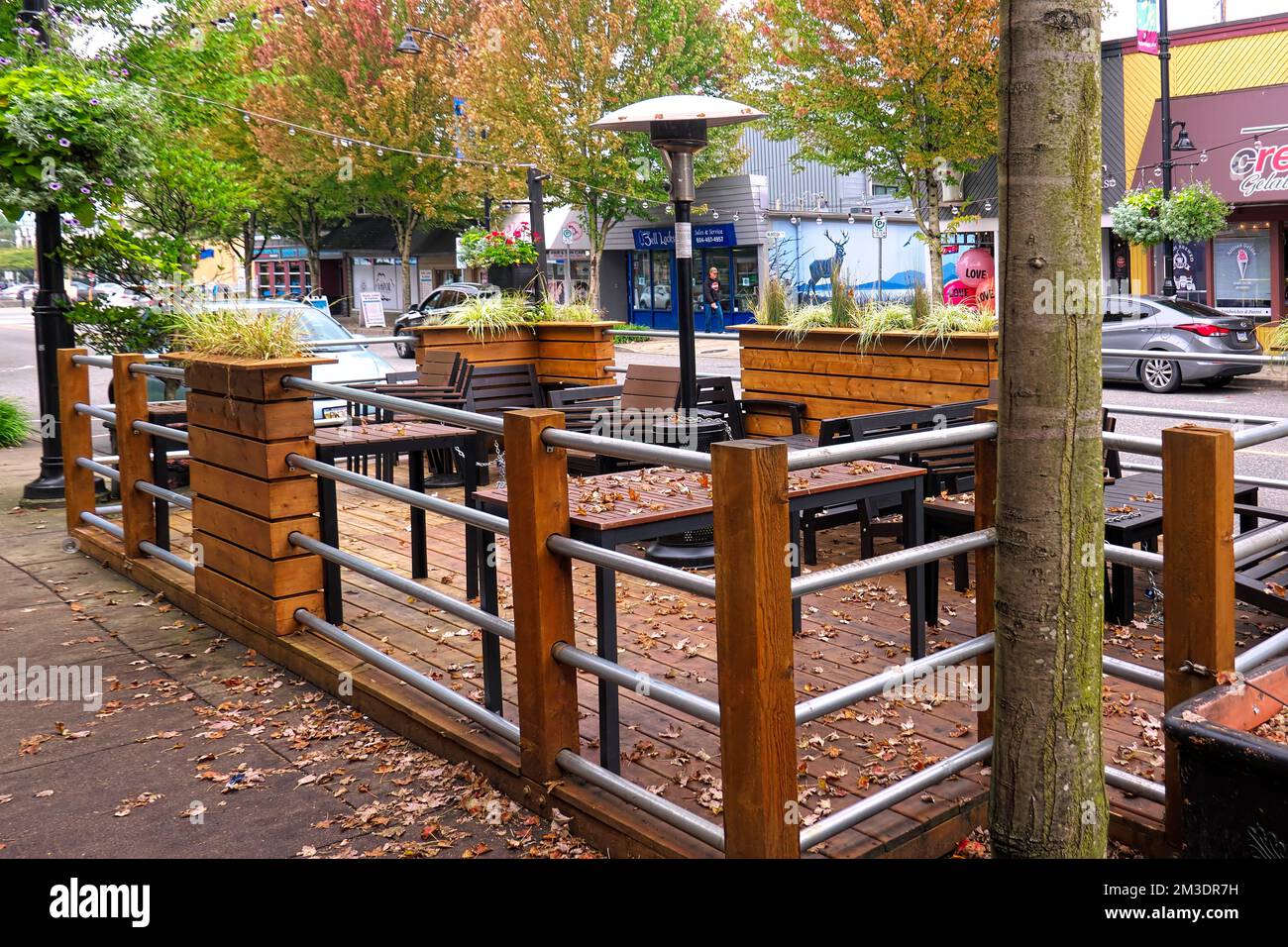 Restaurant Outdoor Patio with Seating and Heat Lamp along a shop-lined street. Maple Ridge, B. C., Canada. Stock Photo