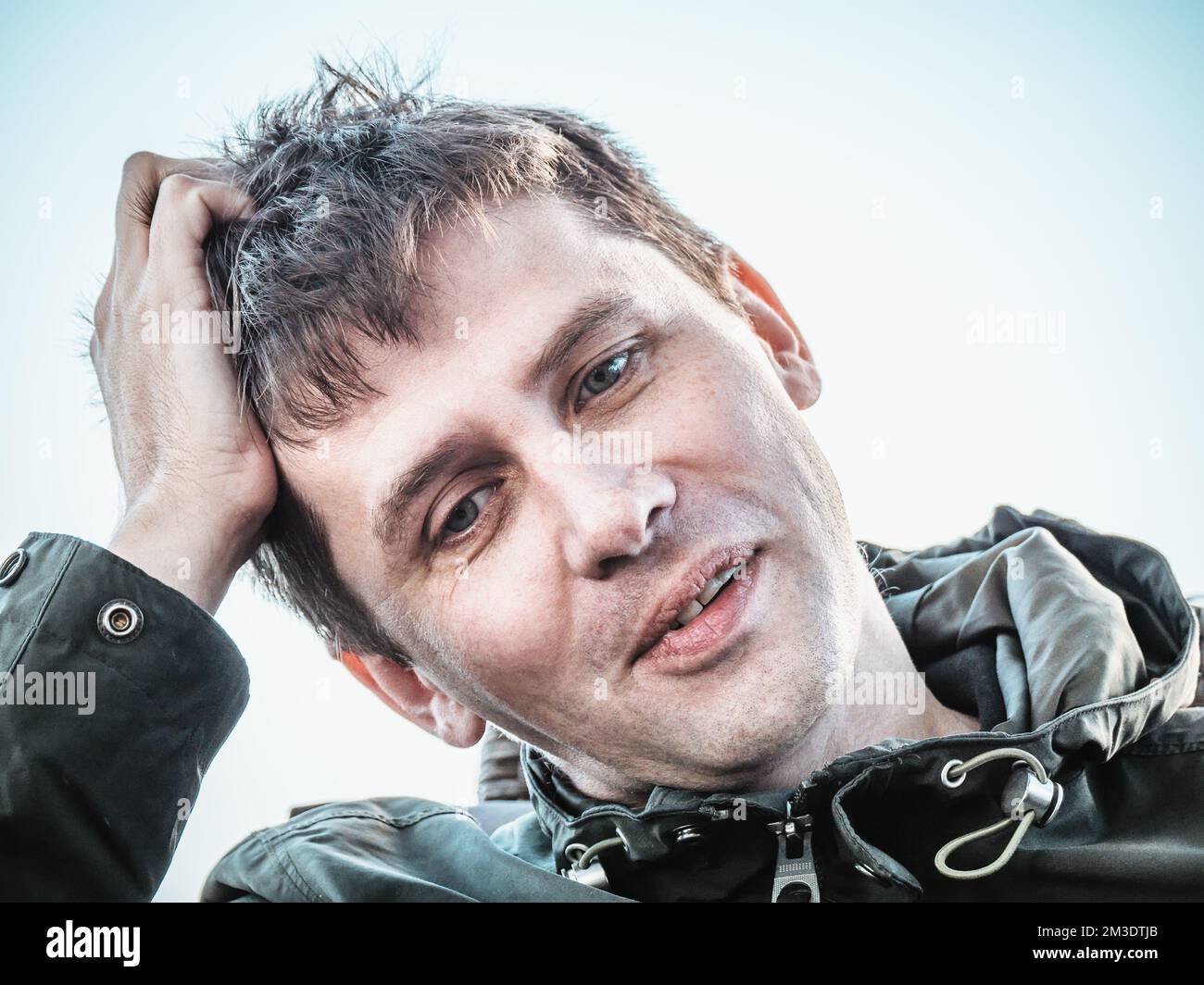 Funny positive young man dreamer holding his head by hand and thinking. Stock Photo