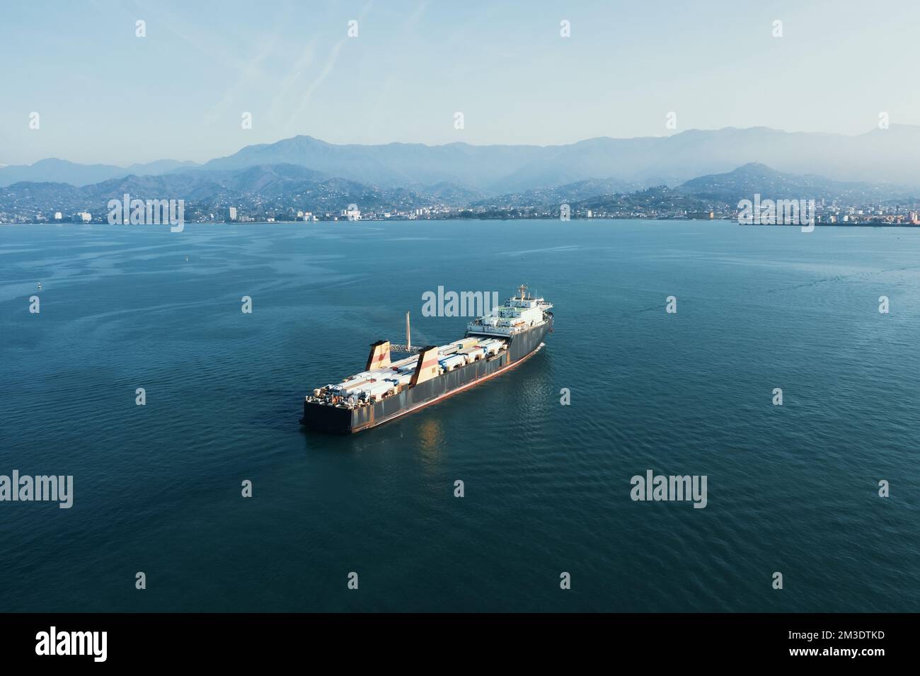 Cargo freight ship with containers and trucks, aerial view from drone. International global delivery and logistic business concept. Stock Photo