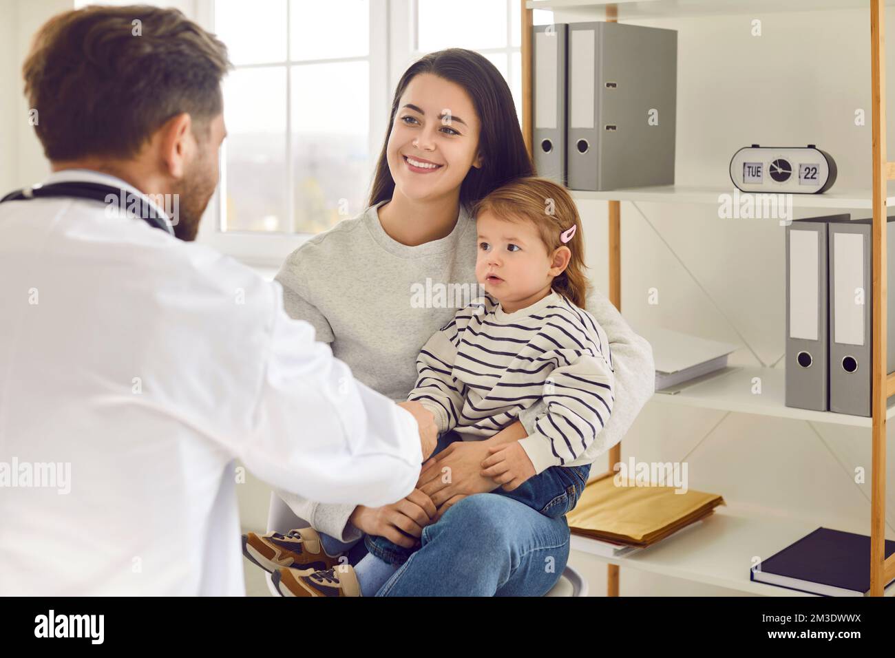 Smiling mother and her two-year-old daughter came for regular checkup at modern hospital. Stock Photo