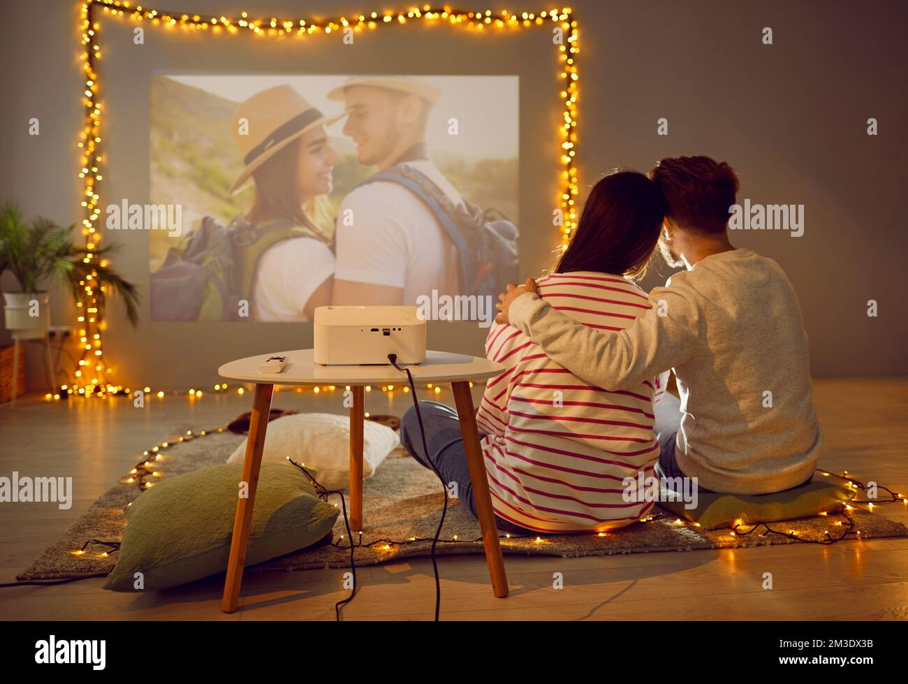 View from behind of couple watching photos with video projector Stock Photo