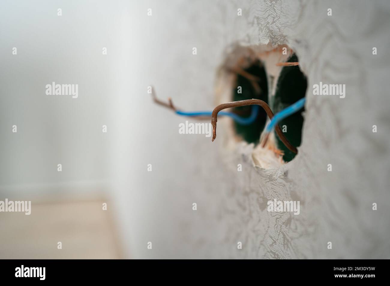 Several exposed electrical copper wires protruding from a whitewall