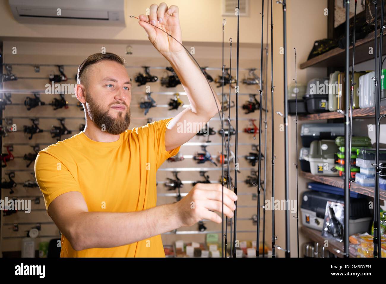 Man chooses ocean fishing rod in the sports shop, copy space Stock Photo
