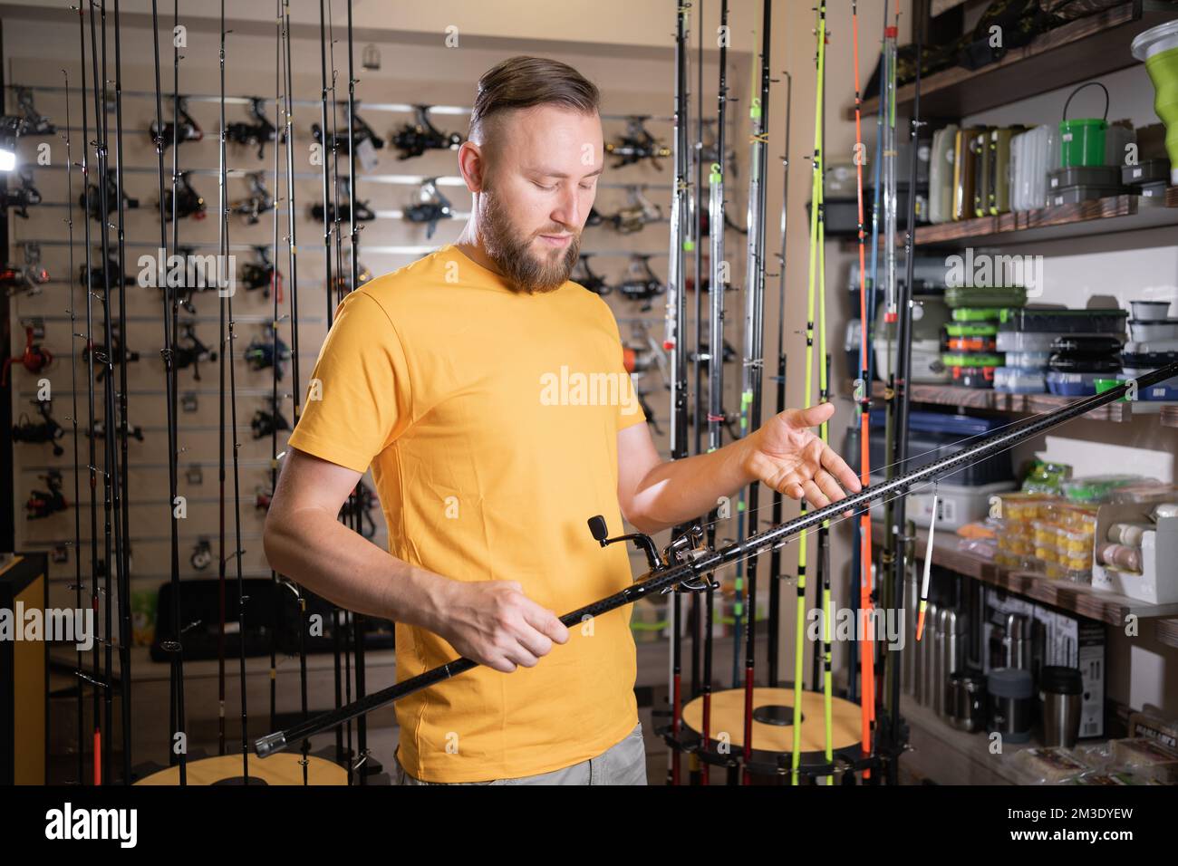Man chooses fishing rod in sports shop, copy space Stock Photo