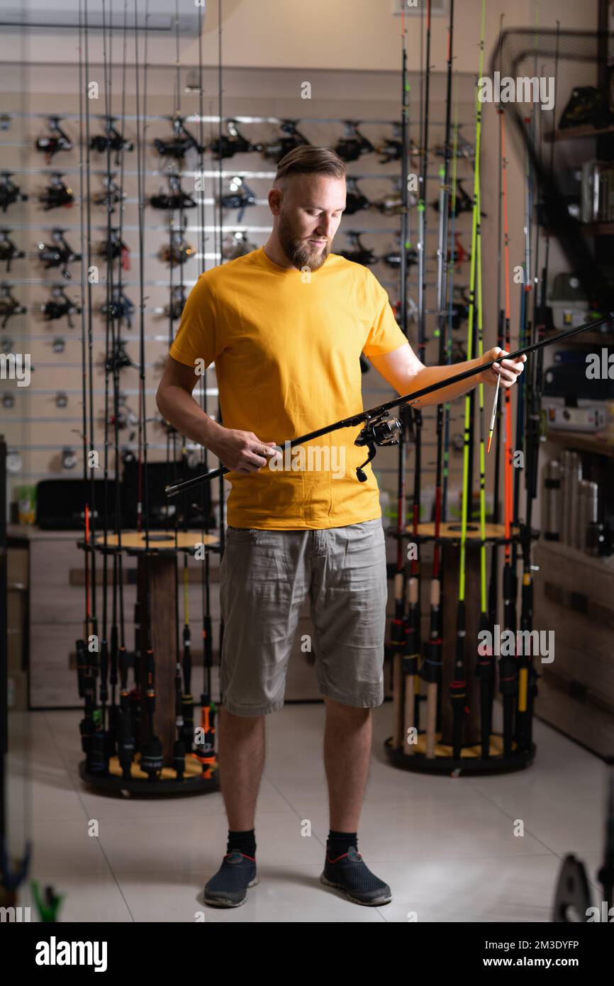 Man chooses fishing rod in the sports shop, copy space Stock Photo