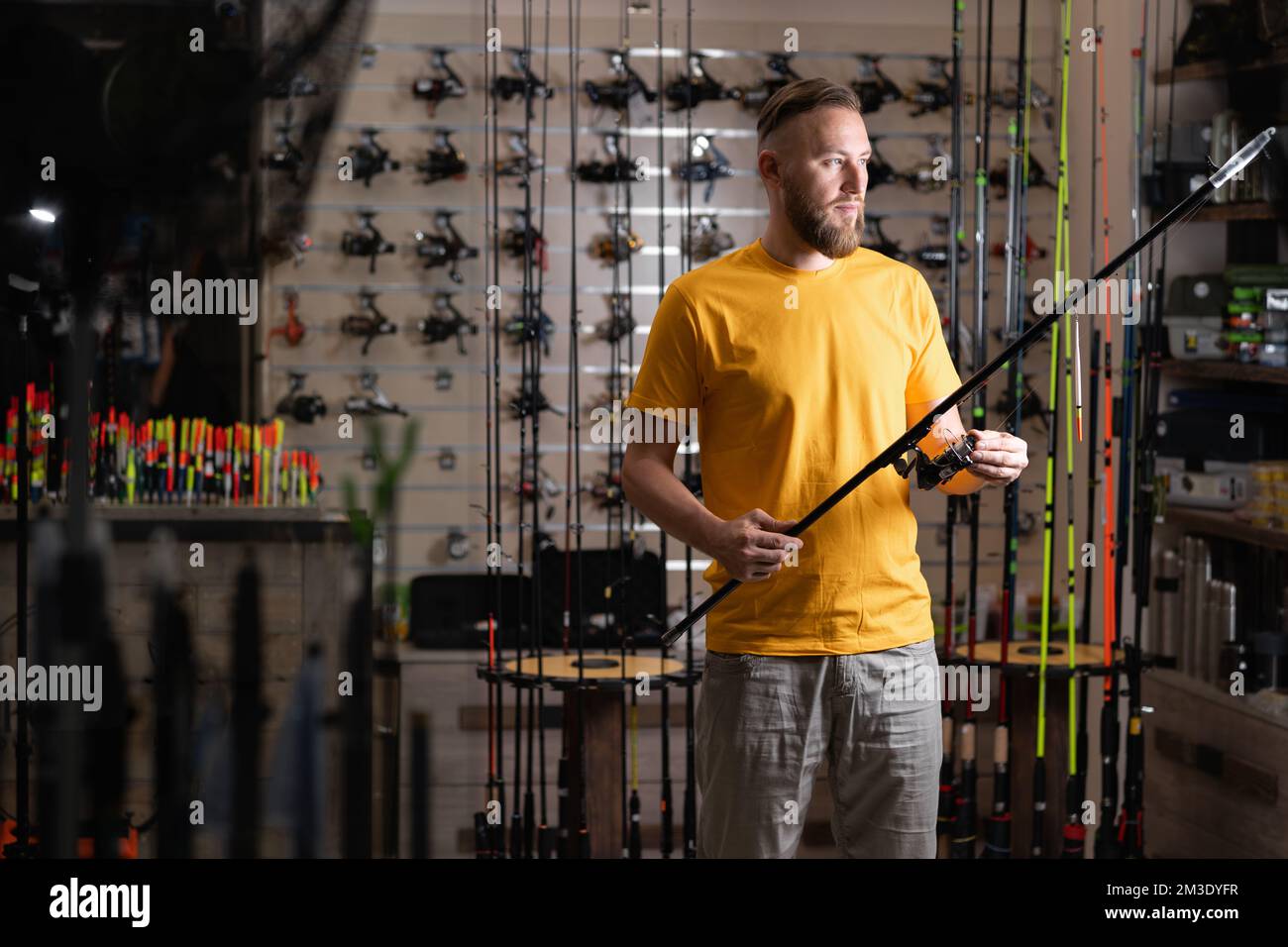 Man shopper choosing fishing rod in fishing store, copy space Stock Photo