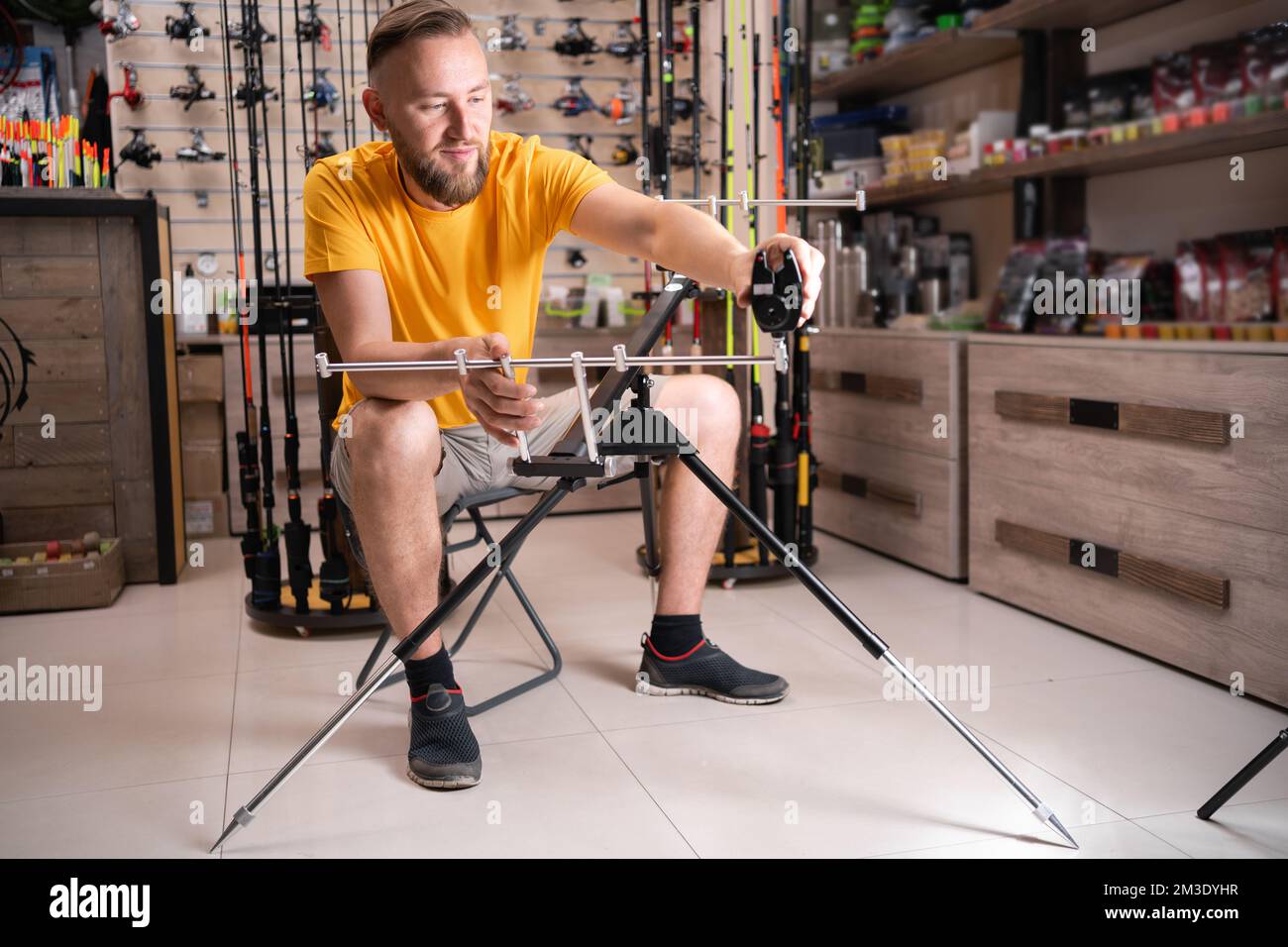 Man fisherman choosing fishing rod stand in sports shop. Copy space Stock Photo