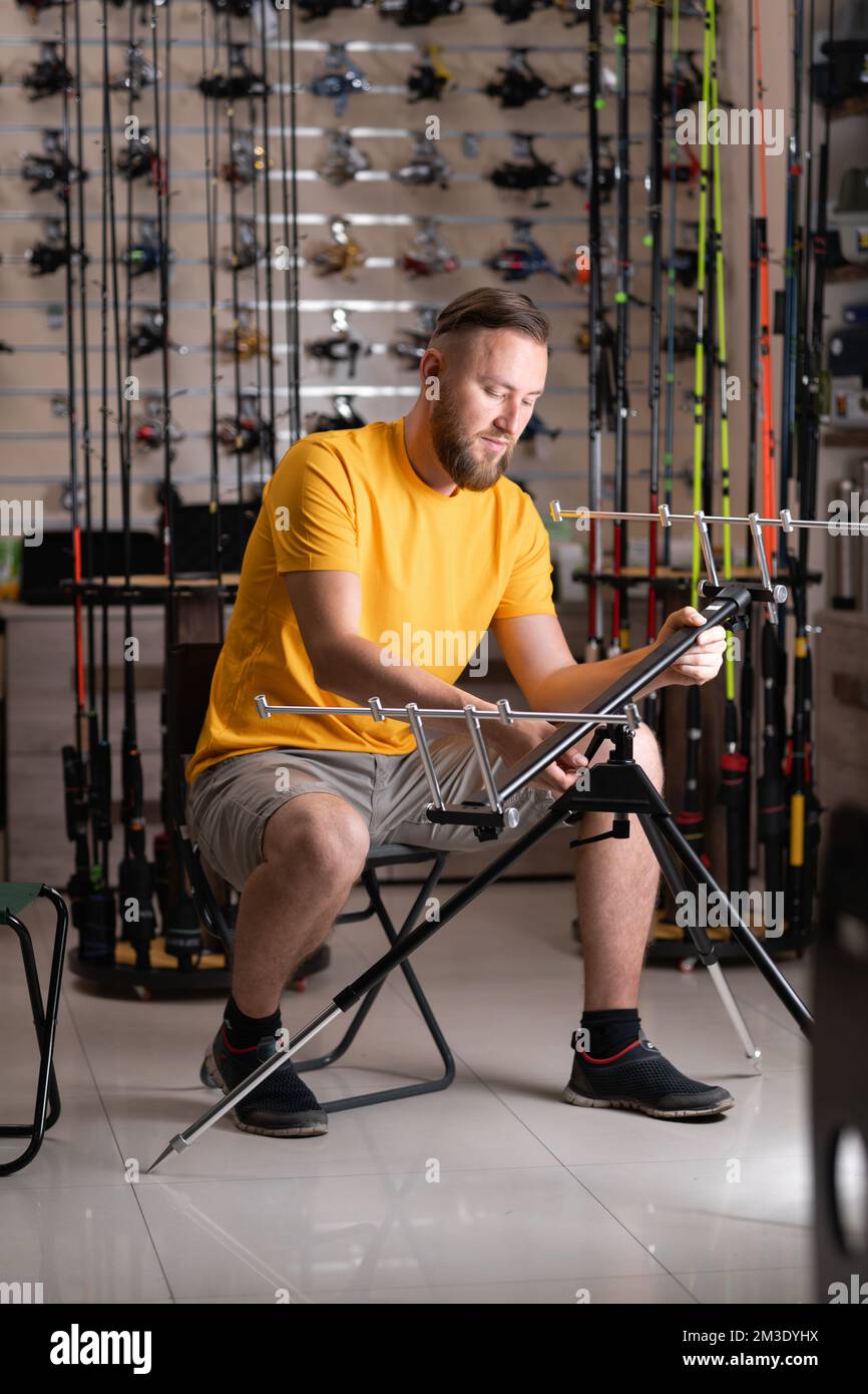 Man choosing fishing rod stand in sports shop. Copy space Stock Photo