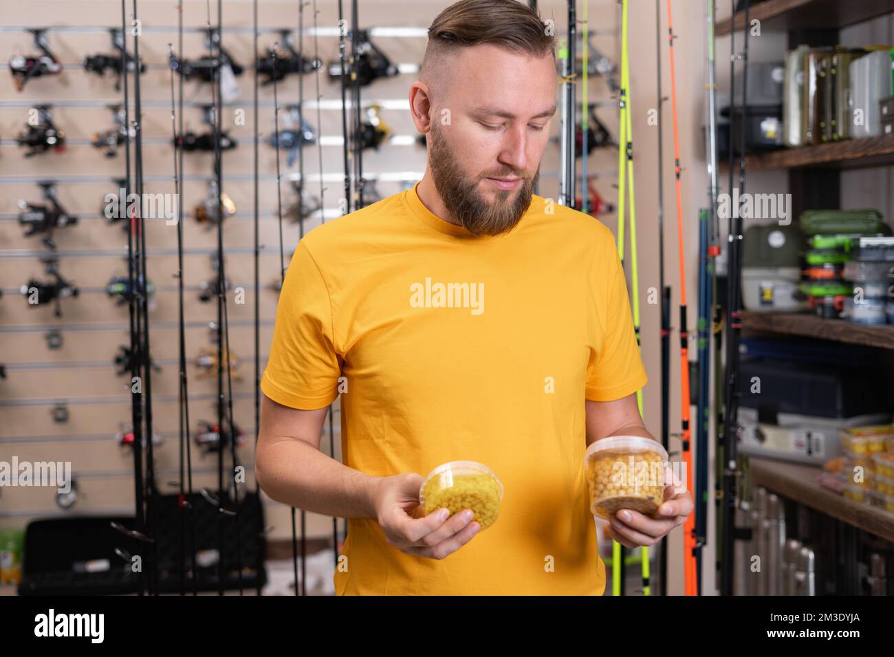 Handsome fisherman choosing fishing bait for fishing in the sports shop. Copy space Stock Photo