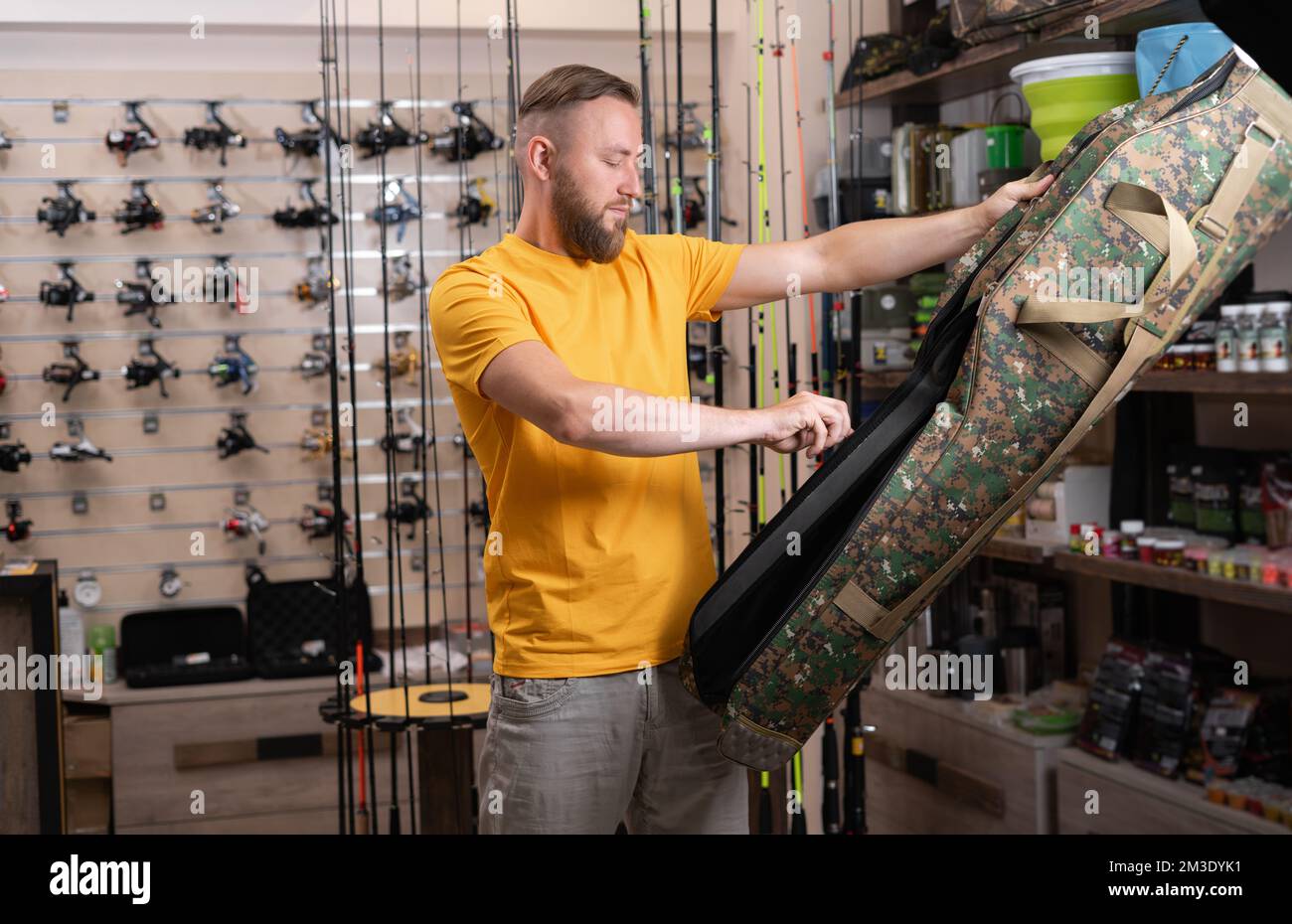 man choosing a fishing rod case in a fishing shop. copy space Stock Photo