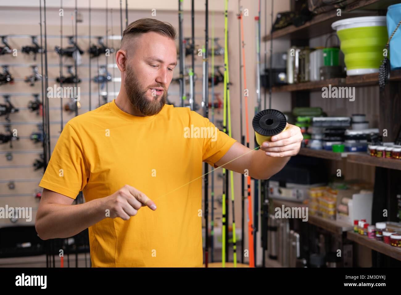 Man buyer choosing fishing accessories in the sports shop. Copy space Stock Photo