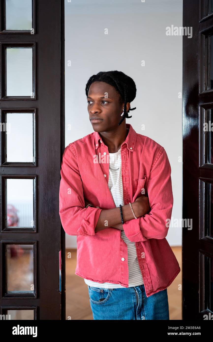 Young pensive African guy standing with crossed arms at home thinking of difficult decision Stock Photo