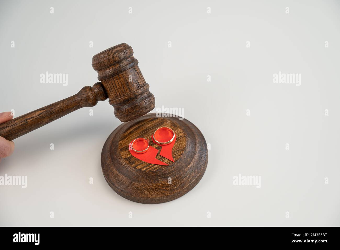The judge hits the gavel on a broken heart and wedding rings Stock