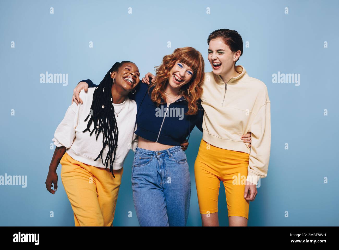 Diverse female friends laughing and having a good time while embracing each other. Group of happy young women enjoying themselves while standing again Stock Photo