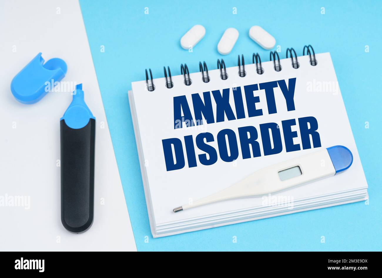 Medical diagnosis concept. On a white-blue surface are pills, a thermometer, a marker and a notebook with the inscription - ANXIETY DISORDER Stock Photo