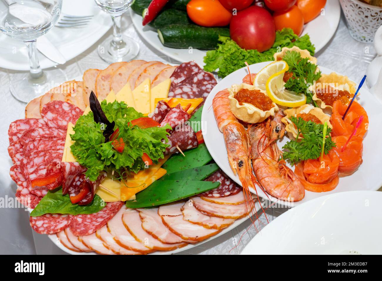 Delicious cold snacks are ready to eat. Cut meat and seafood on the festive table. Stock Photo