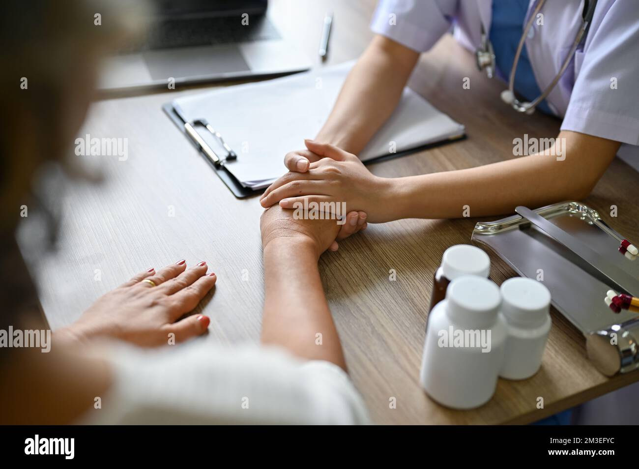 A female doctor holding her patient's hands on the table while discussing the treatment plan. cropped and close-up image Stock Photo