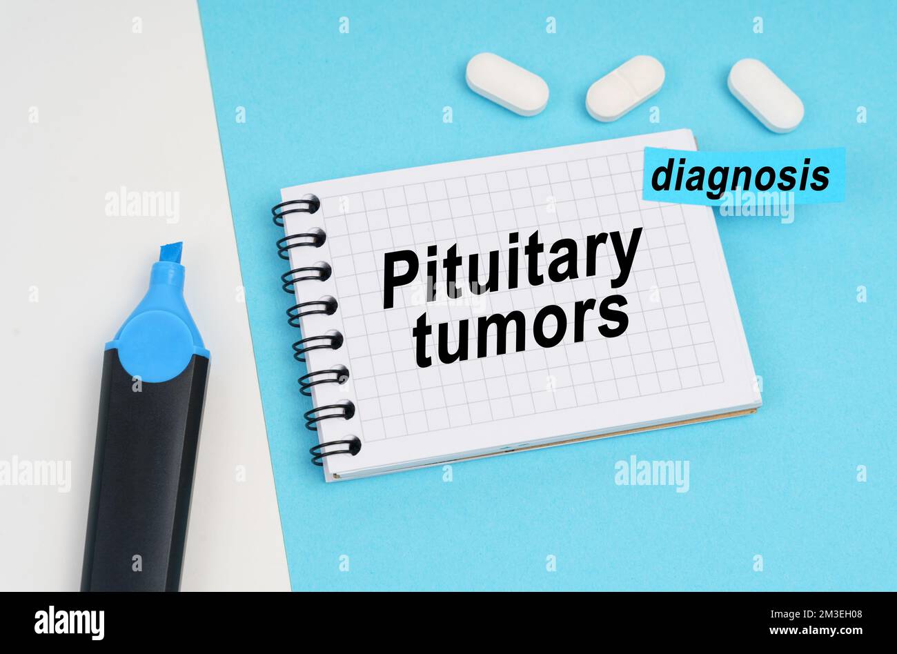 Medicine and health concept. On a white and blue surface are pills, a marker and a notebook with the inscription - pituitary tumors, a sticker with th Stock Photo