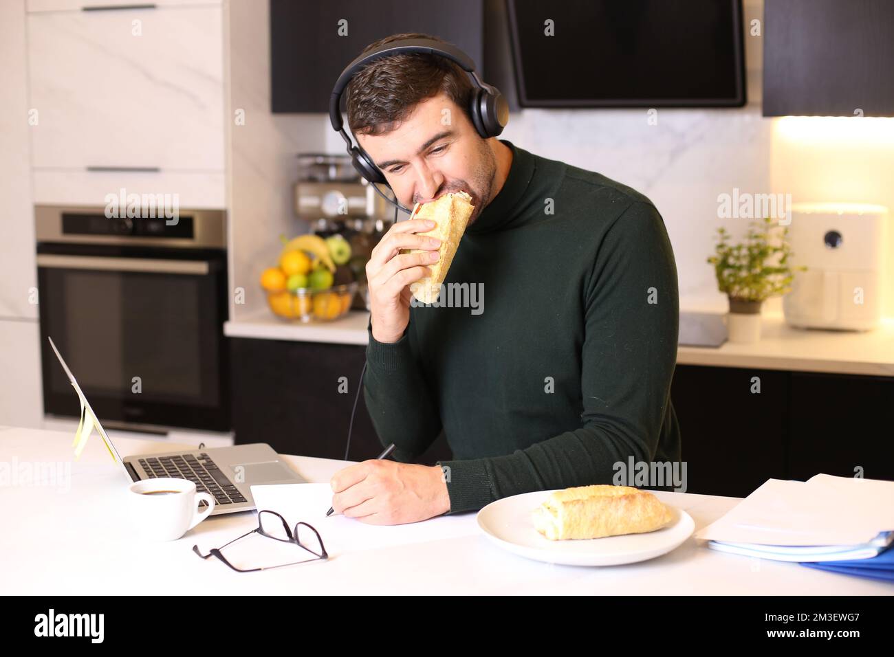 Busy man eating a sandwich while on conference call Stock Photo