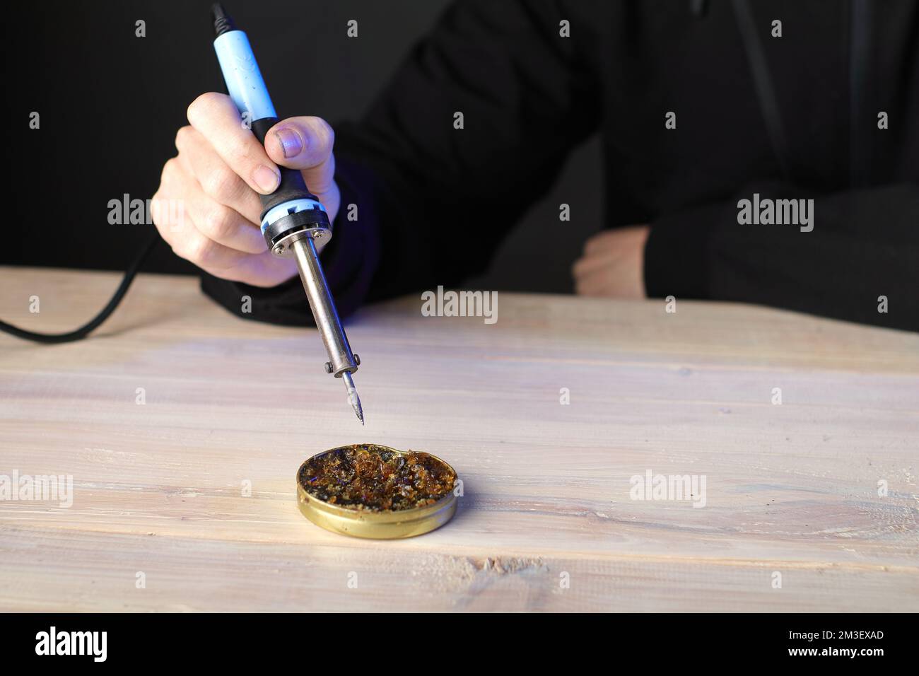 resistance soldering iron in hand over rosin and gray background Stock