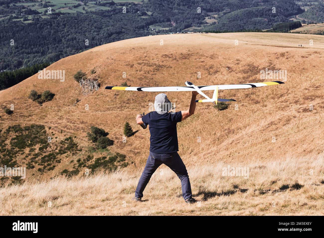 A closeup of a man launches a radiocontrolled model glider during an