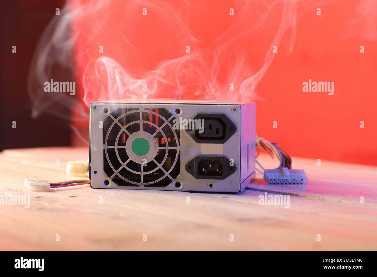 old computer power supply burning on the table and pink background ...