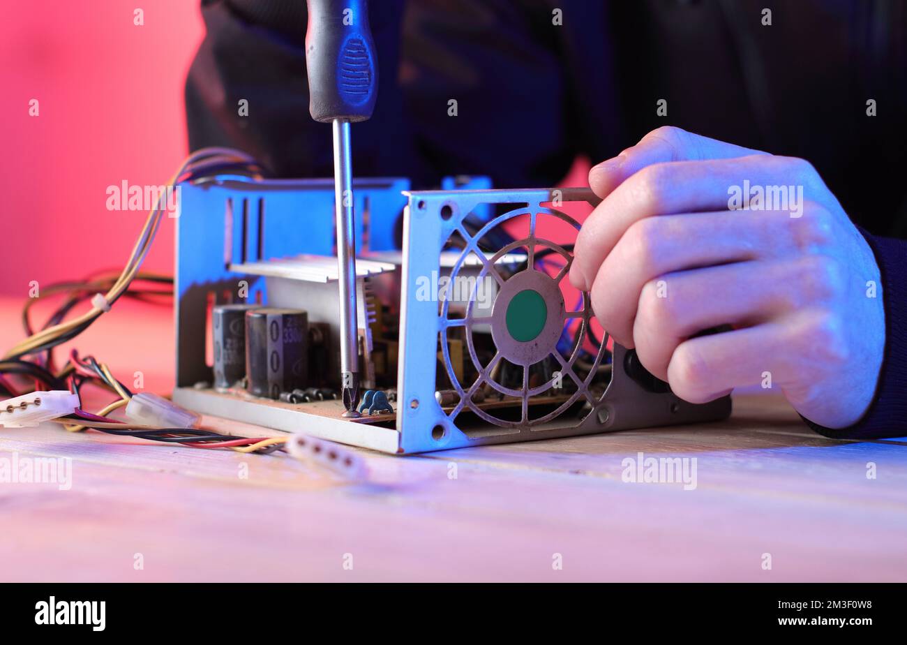 disassembly of a computer power supply on a table by a person and a