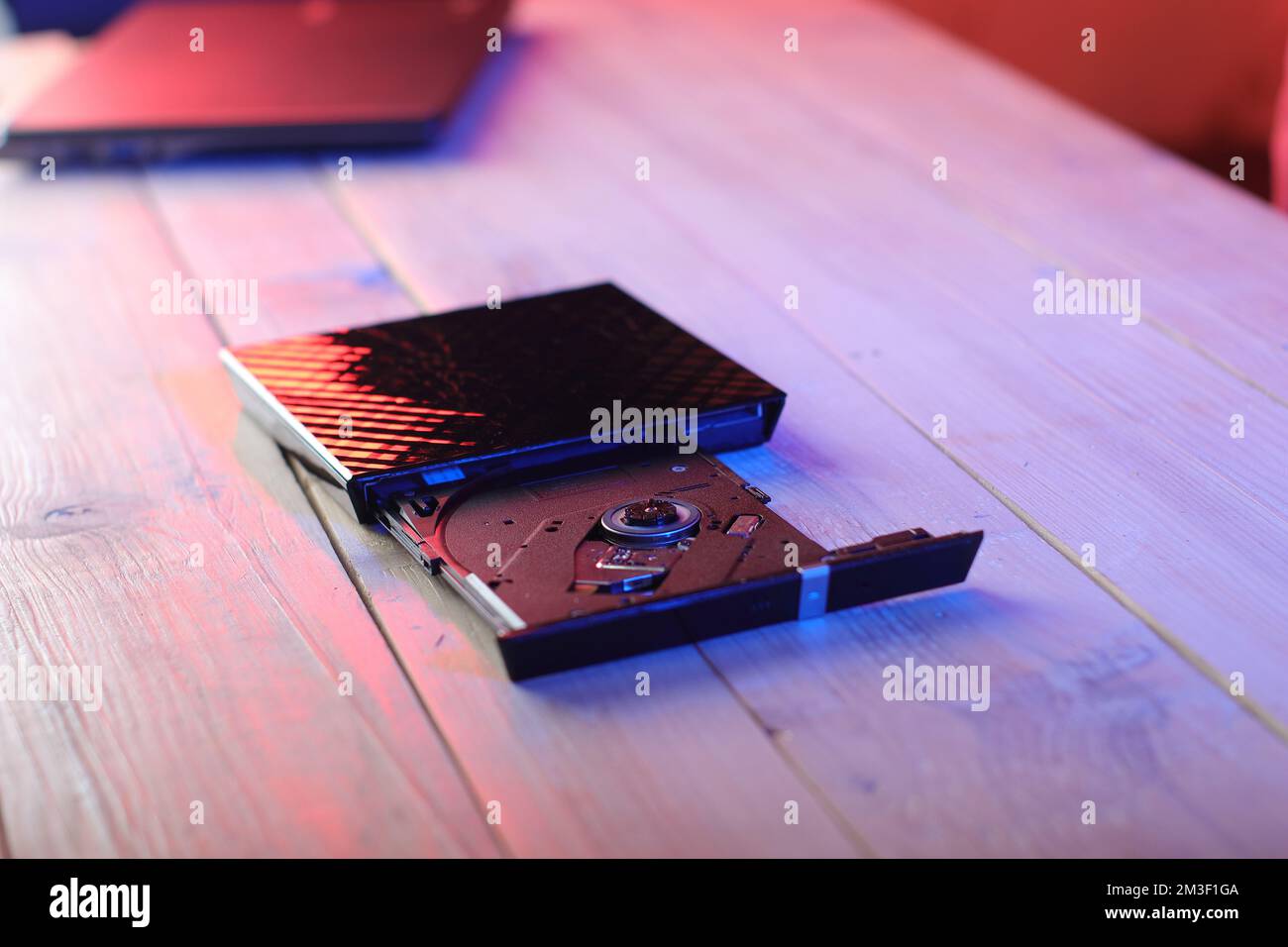 laptop optical drive with open tray on table and colored background