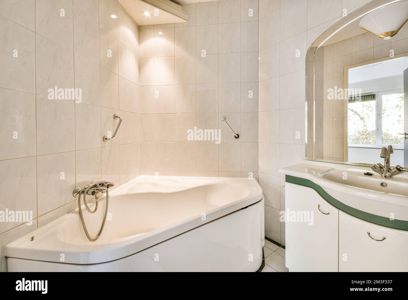 a bathroom with white tiles and green trim around the tub, sink, and