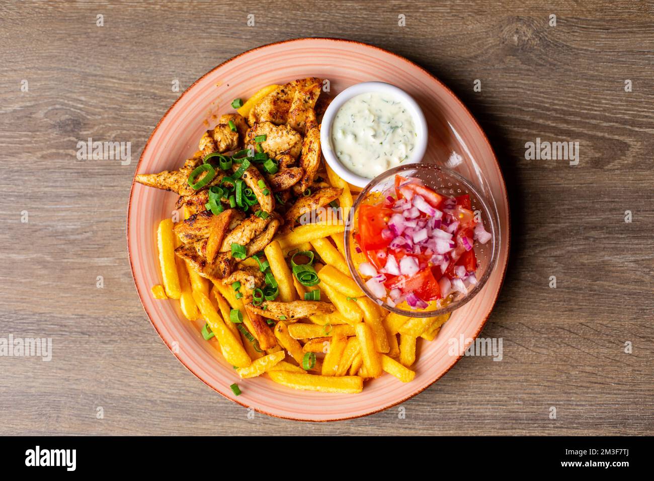 French fries, white garlic sauce, vegetable salad bowl on pink plate. Fresh appetizing, yummy, tasty plate of fast food Stock Photo