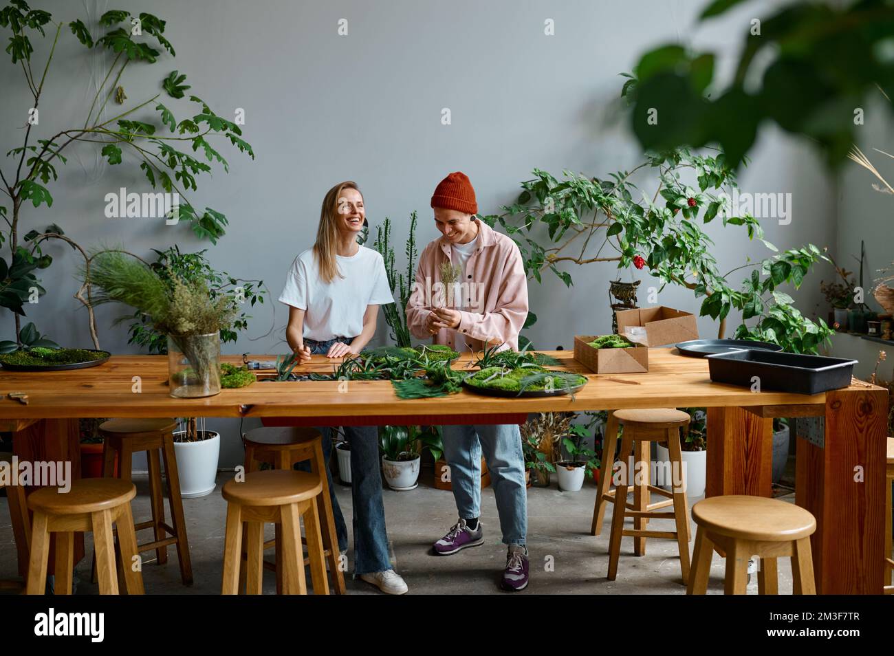 Two happy and smiling young florists working together at creative workshop Stock Photo