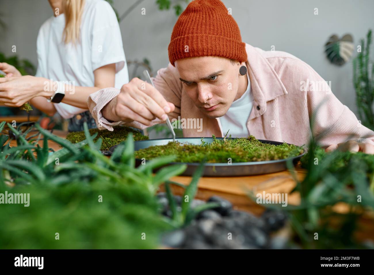 Experienced male florist working on circle plant panel closeup Stock Photo