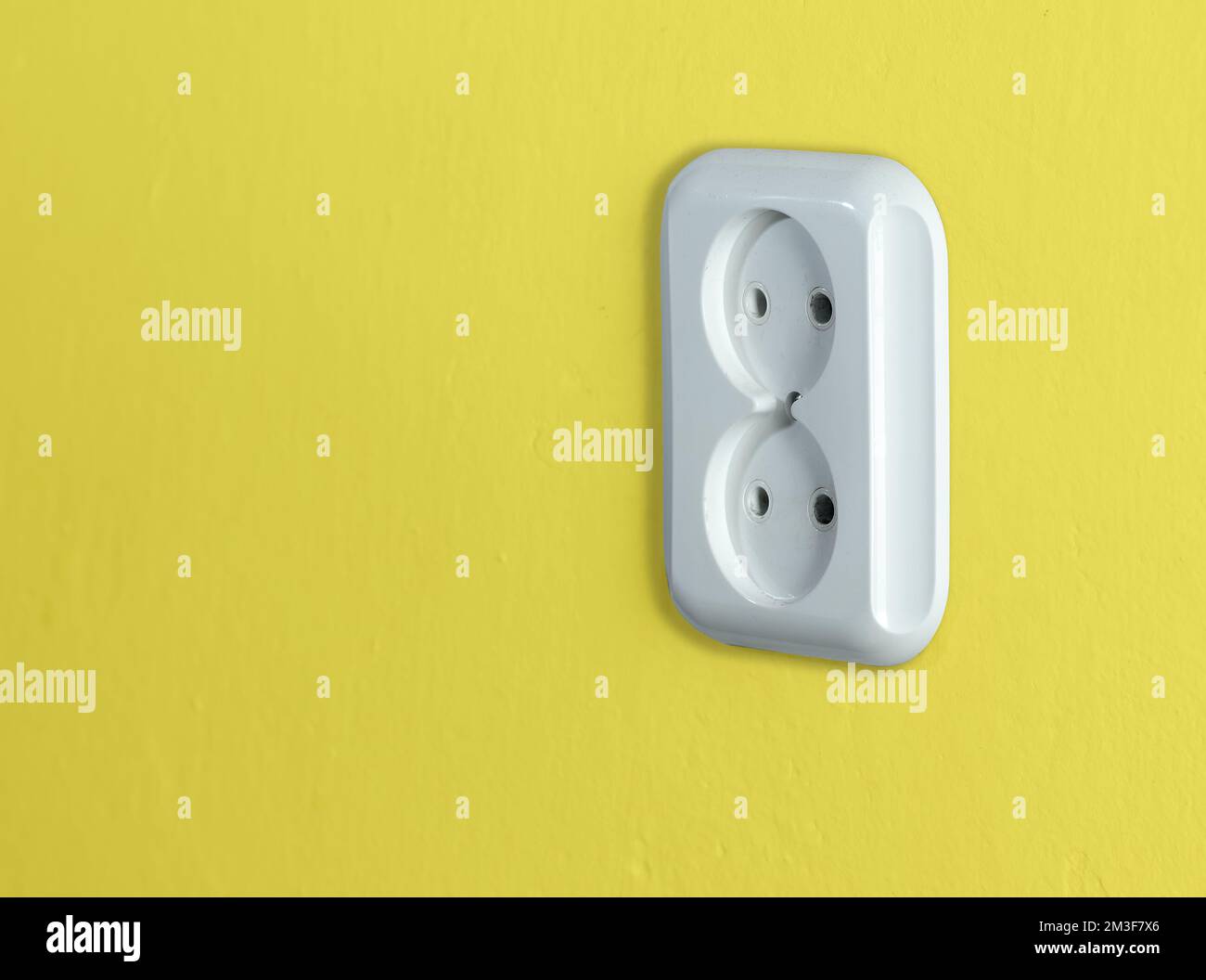 white two-port socket on the yellow wall Stock Photo