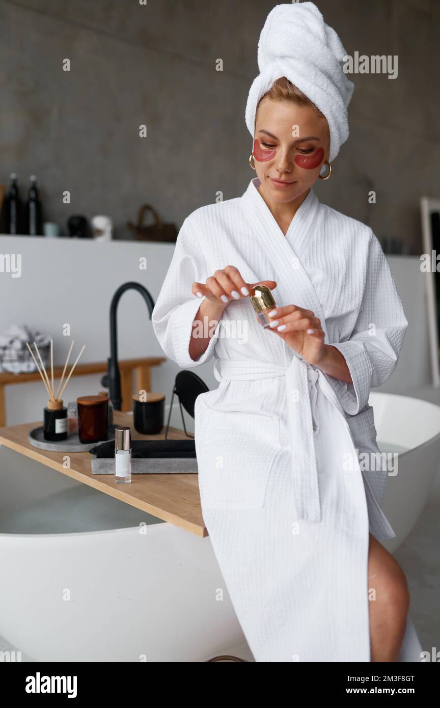 Young woman applying beauty patch under eyes after taking bath Stock Photo