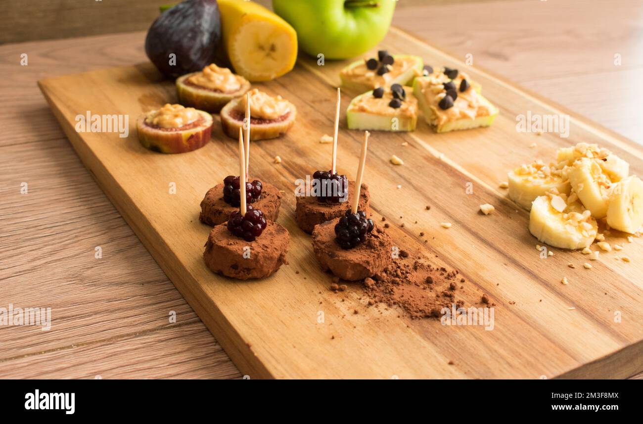 Presentation of fruits with peanut butter on a wooden board, healthy